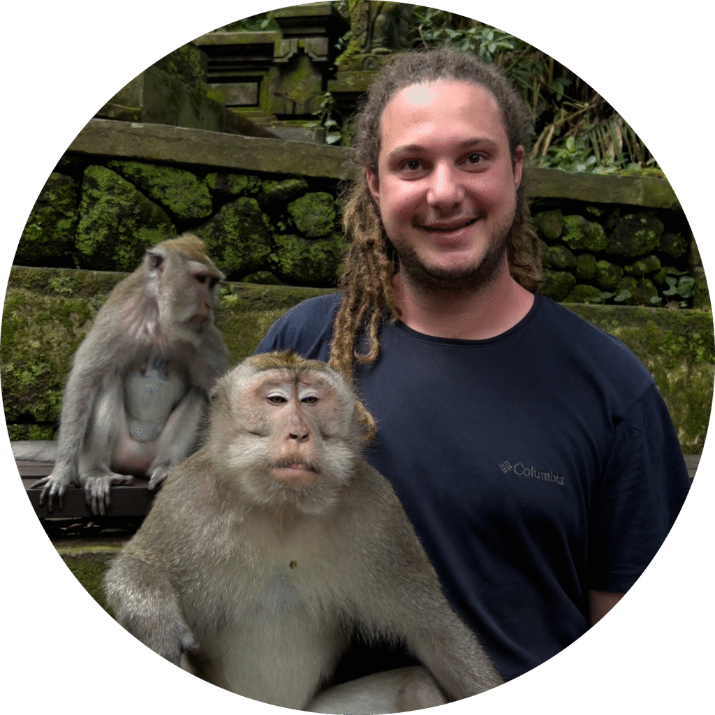 Smiling traveler posing with Balinese monkeys at the Sacred Monkey Forest in Ubud, Bali — used as profile photo on the travel introduction page.
