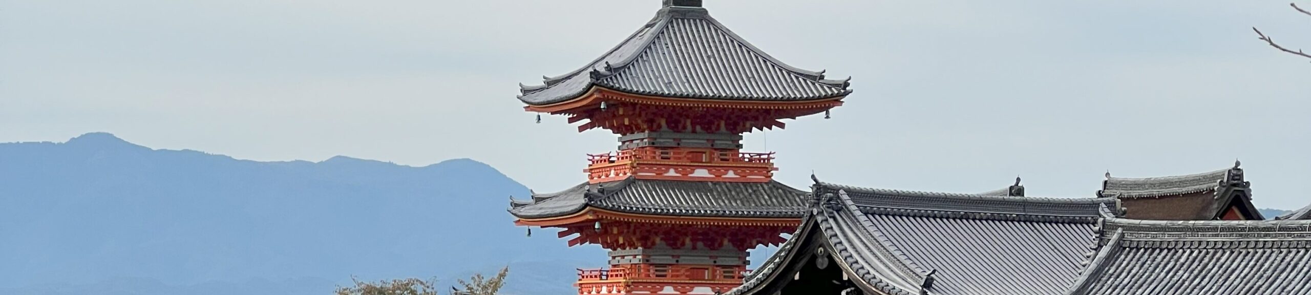 Rooftop of the historic Kiyomizu-dera Temple in Kyoto with mountain scenery in the background, used as a header image for the travel introduction page.